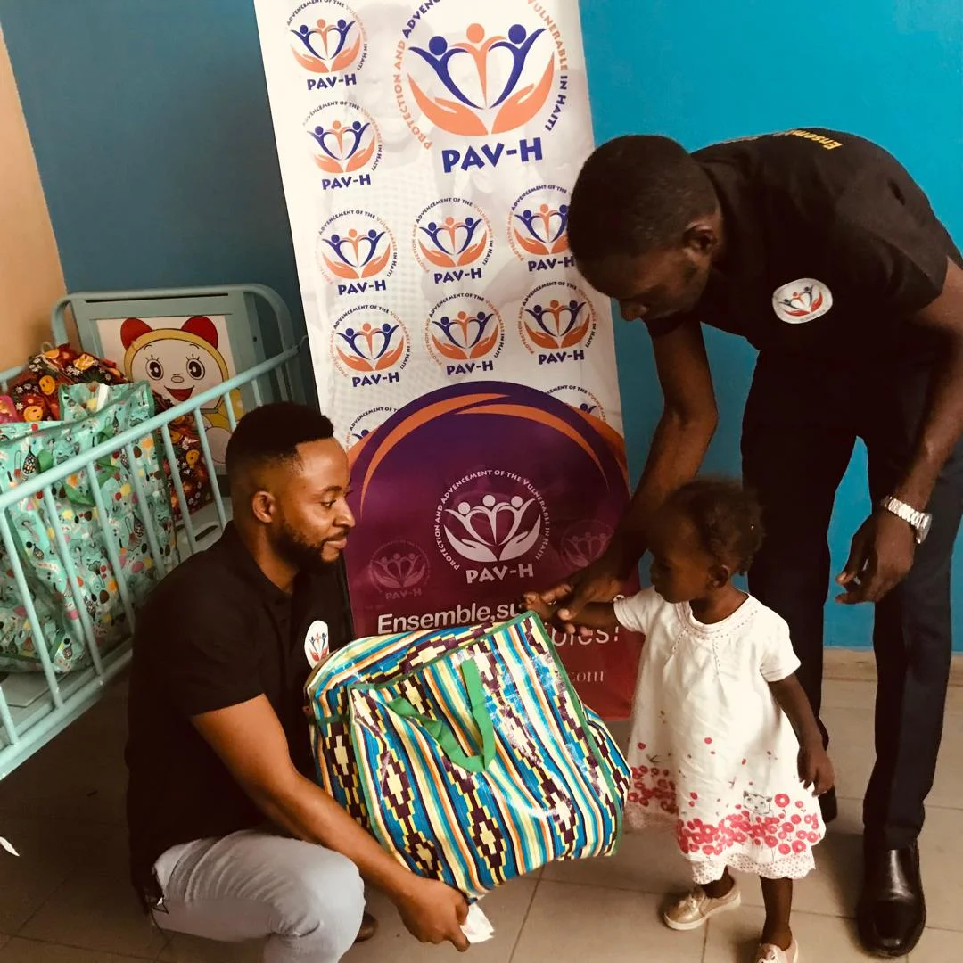 PAV-H members handing a bag to a little girl at La Paix Hospital