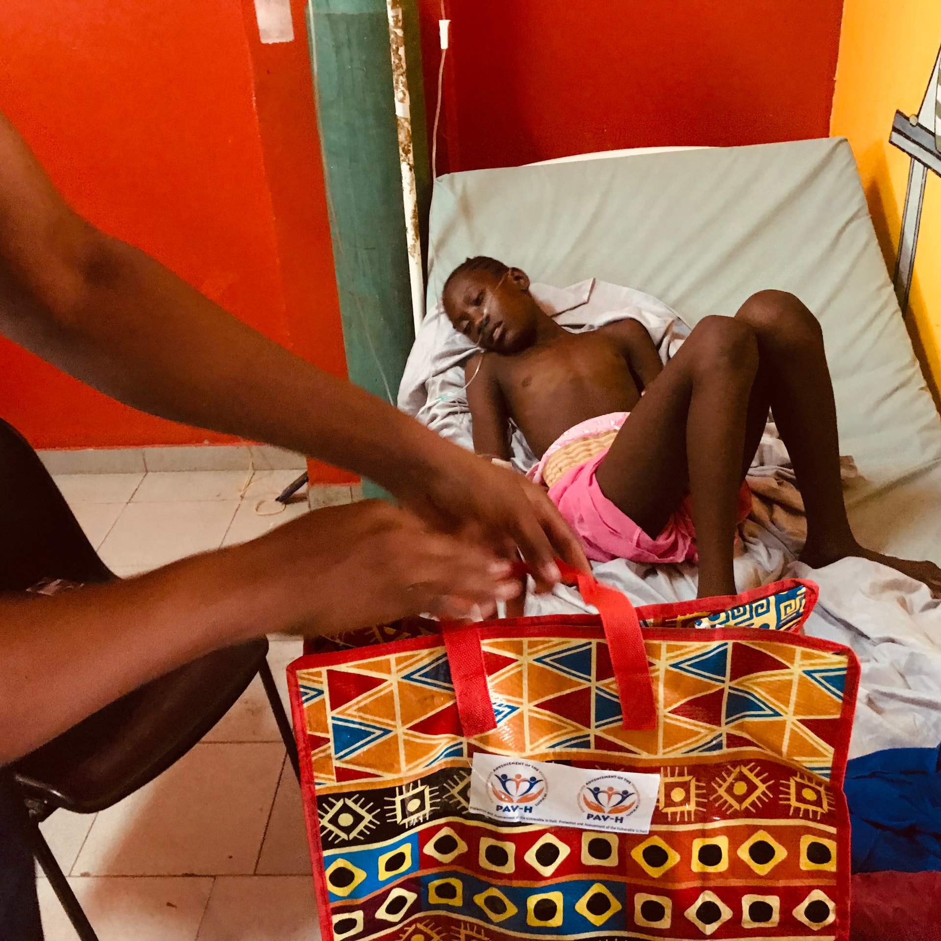 Un enfant hospitalisé reçoit un kit d'aide PAV-H déposé à son chevet par un bénévole