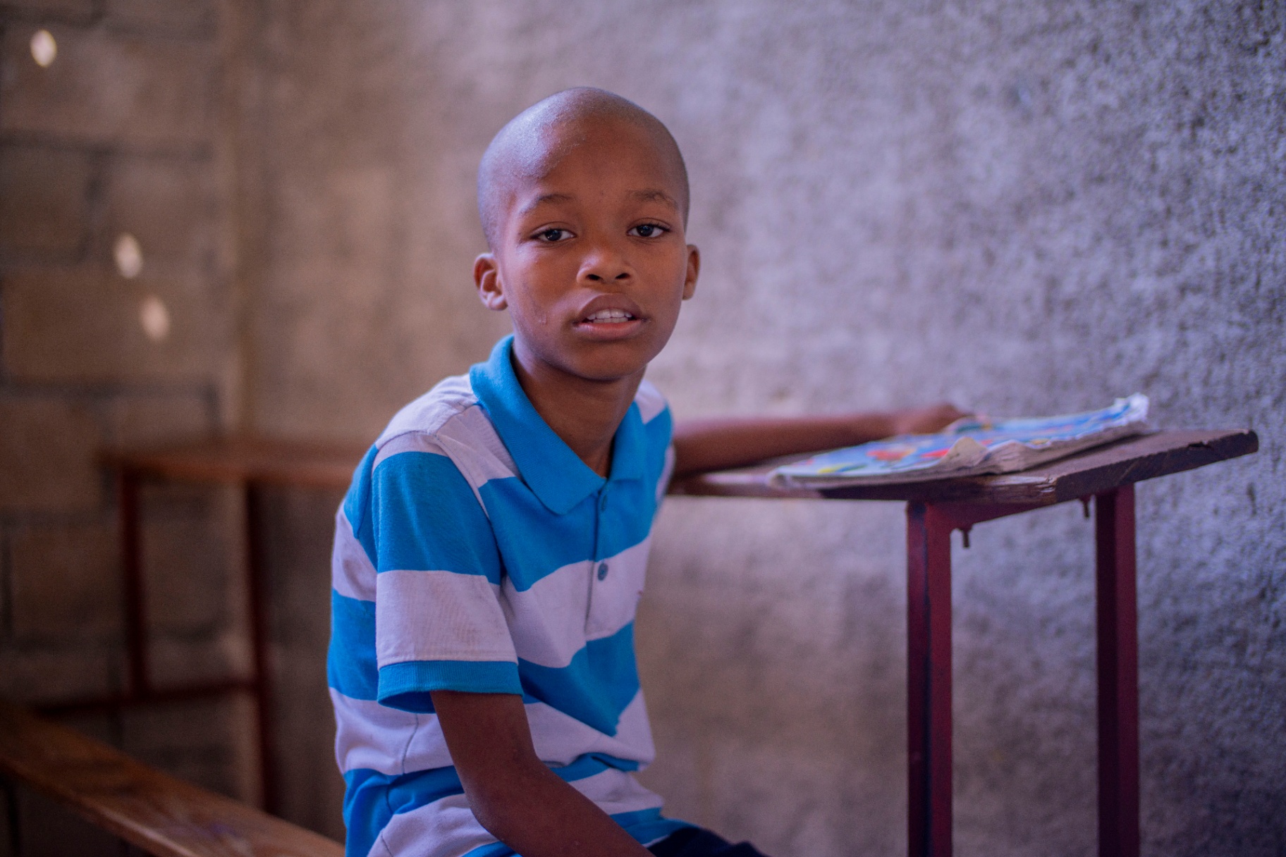 Haitian student leaning on his desk in class
