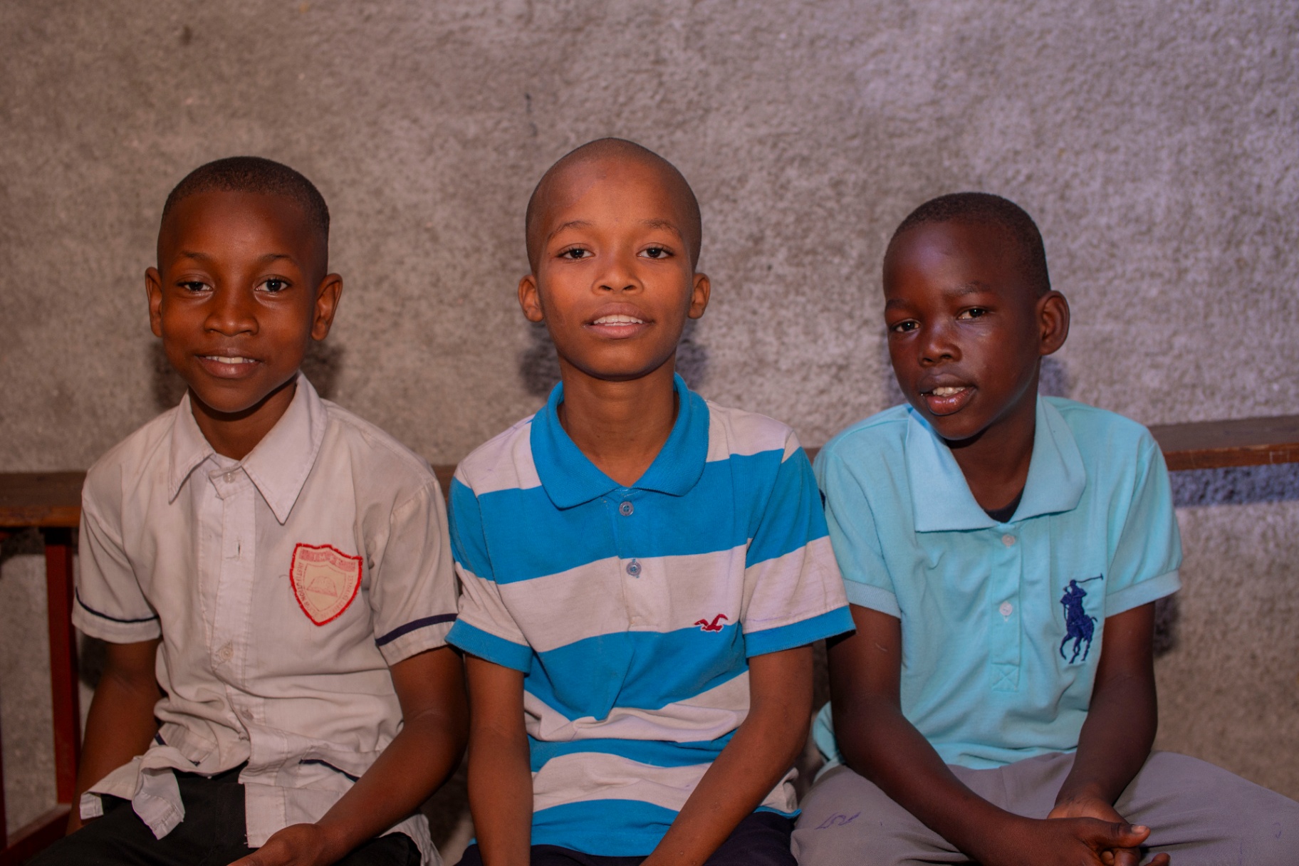 Three young boys posing together in a classroom