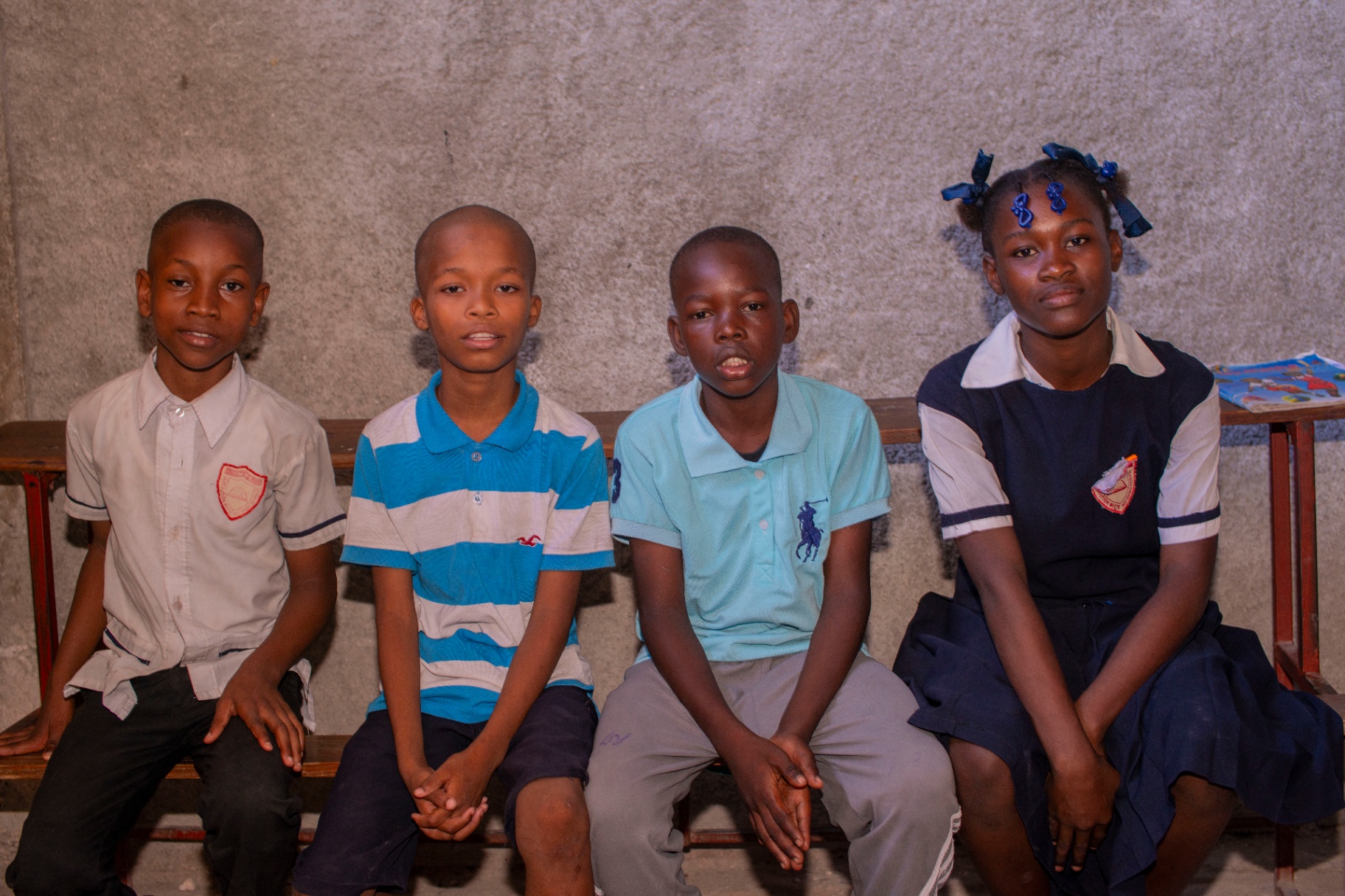 Group of Haitian students sitting on a bench in a classroom